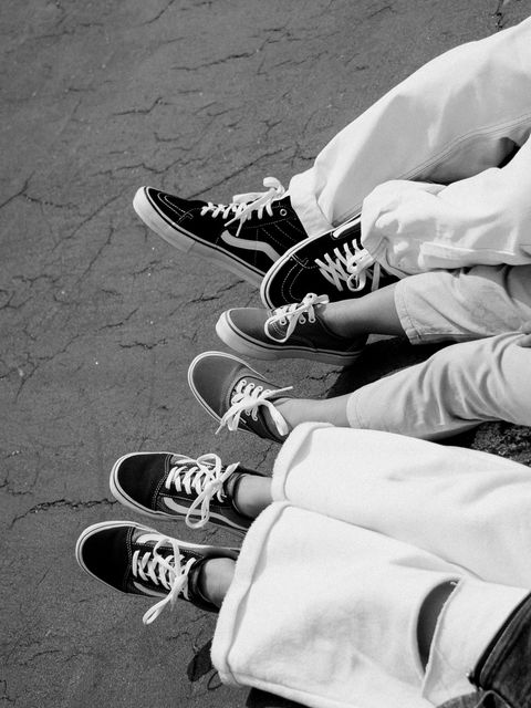 Em preto e branco, detalhe dos pés do pai e das crianças sentados lado a lado, todos de tênis Vans.